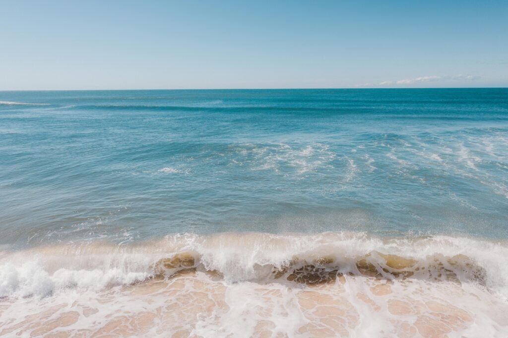 Turquoise water of ocean washing sandy coast under cloudless blue sky in daytime